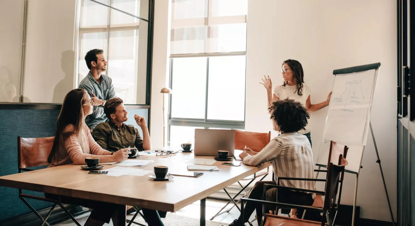 Woman presenting in a conference room to her colleagues.