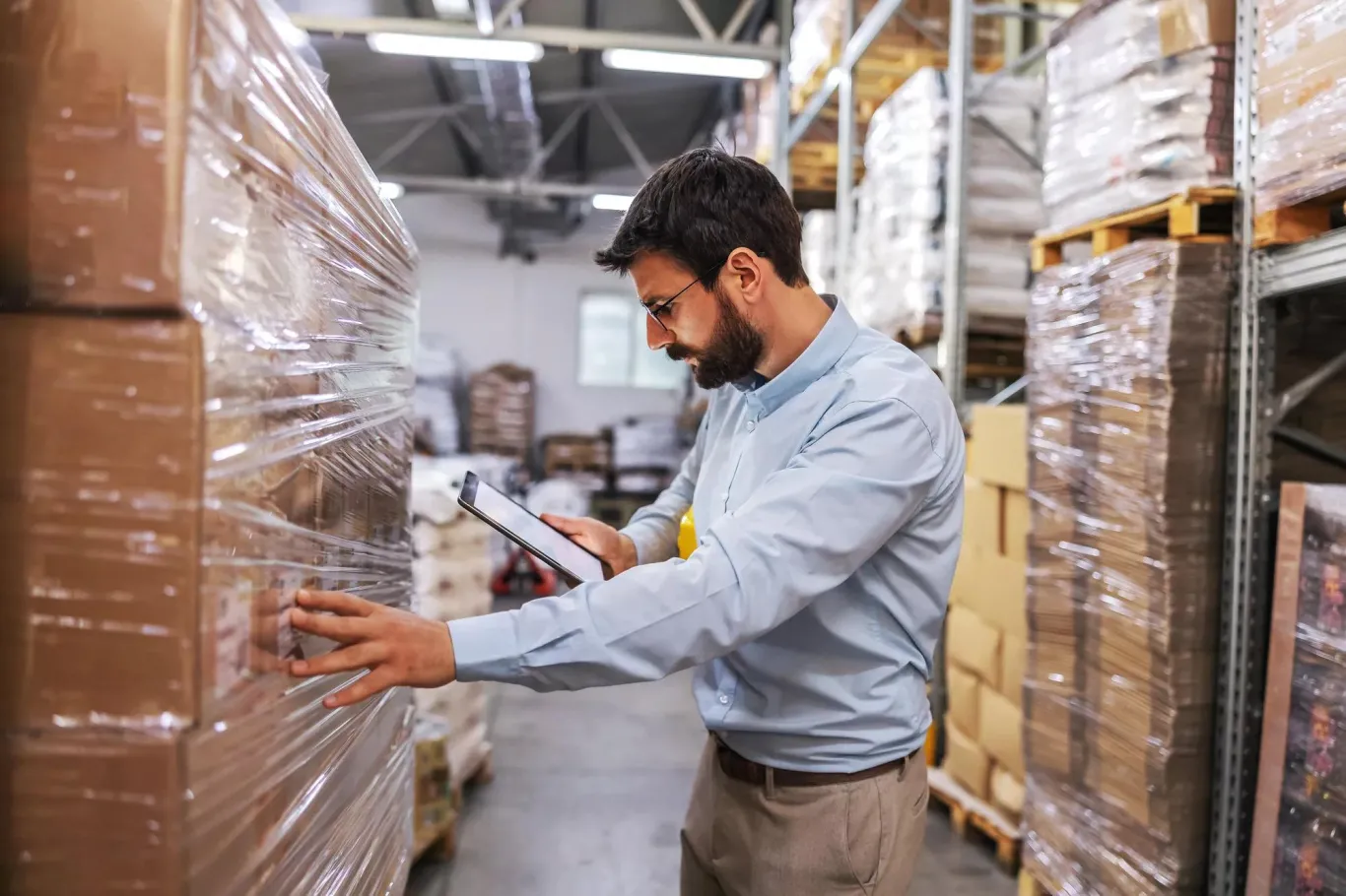 A man in a warehouse setting checking inventory.