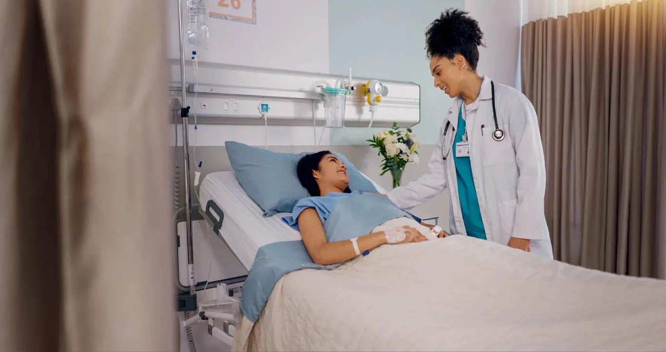 Patient in hospital bed receiving consultation from her doctor.