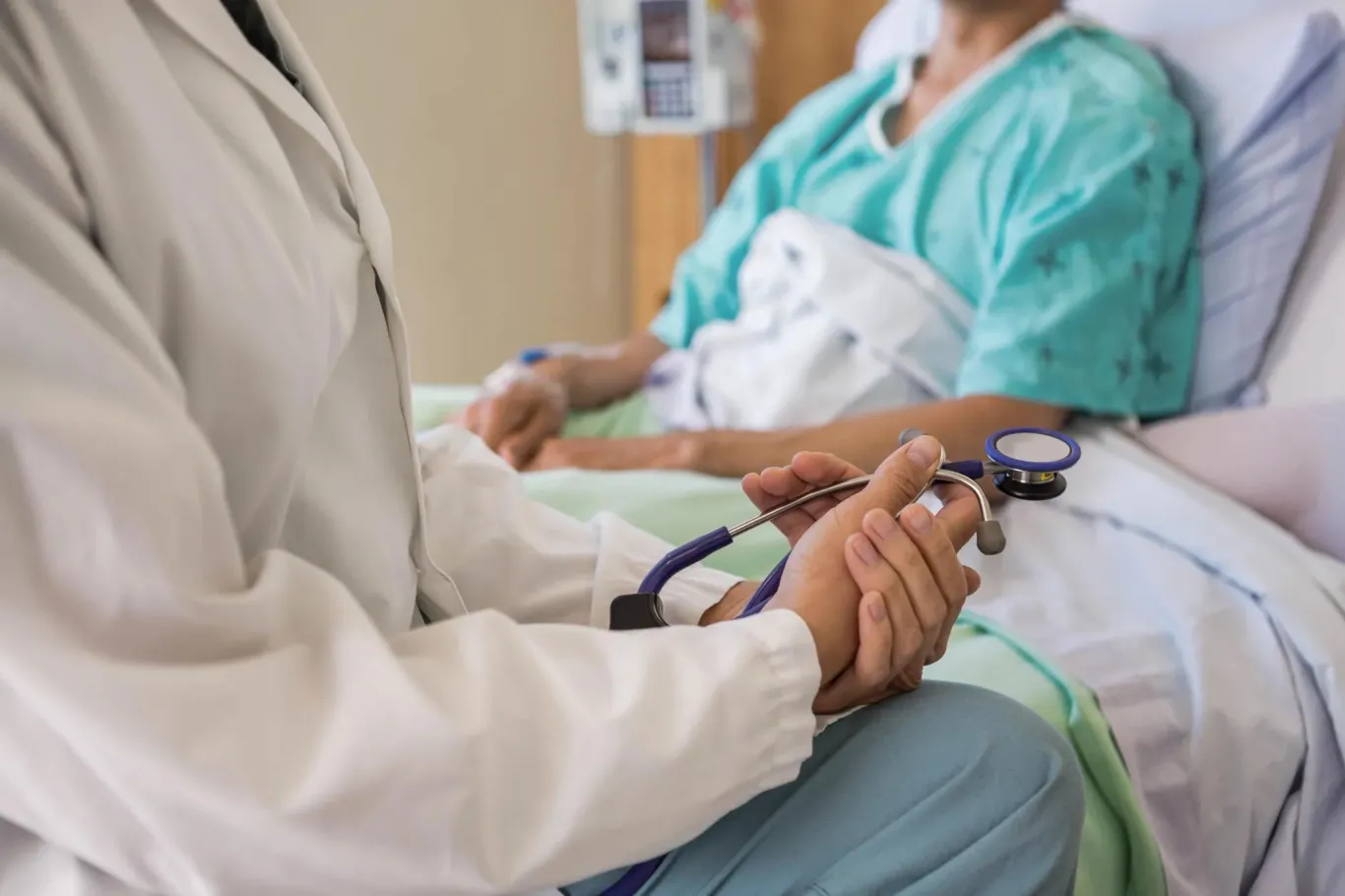 Patient in hospital bed receiving consultation from doctor.