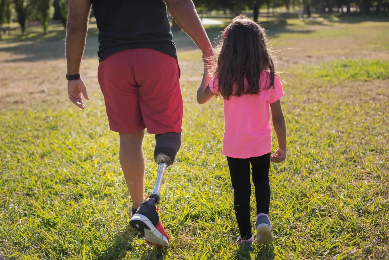 Man with artificial leg walking with young girl.