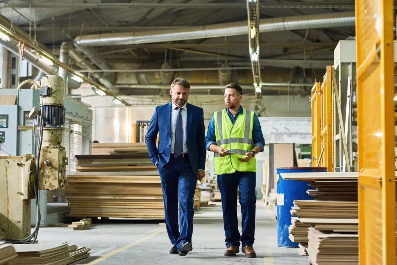 A businessmen and a construction worker walking and discussing the project they are working on