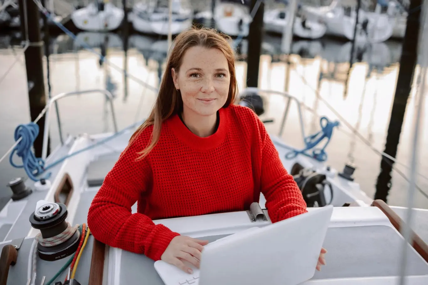 Woman working on her laptop on a boat at dusk