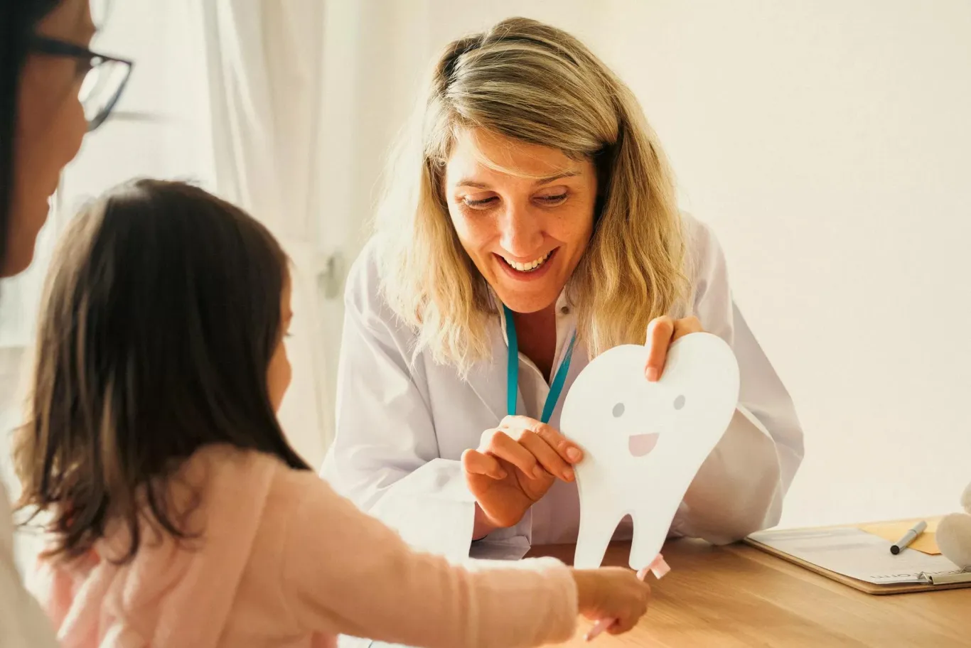 Smiling dentist helping a child understand the importance of good dental hygiene.