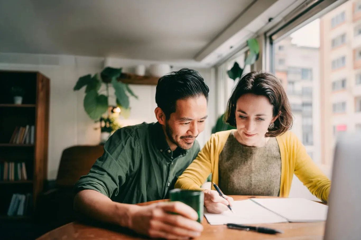 Two people seated together at a wooden table.