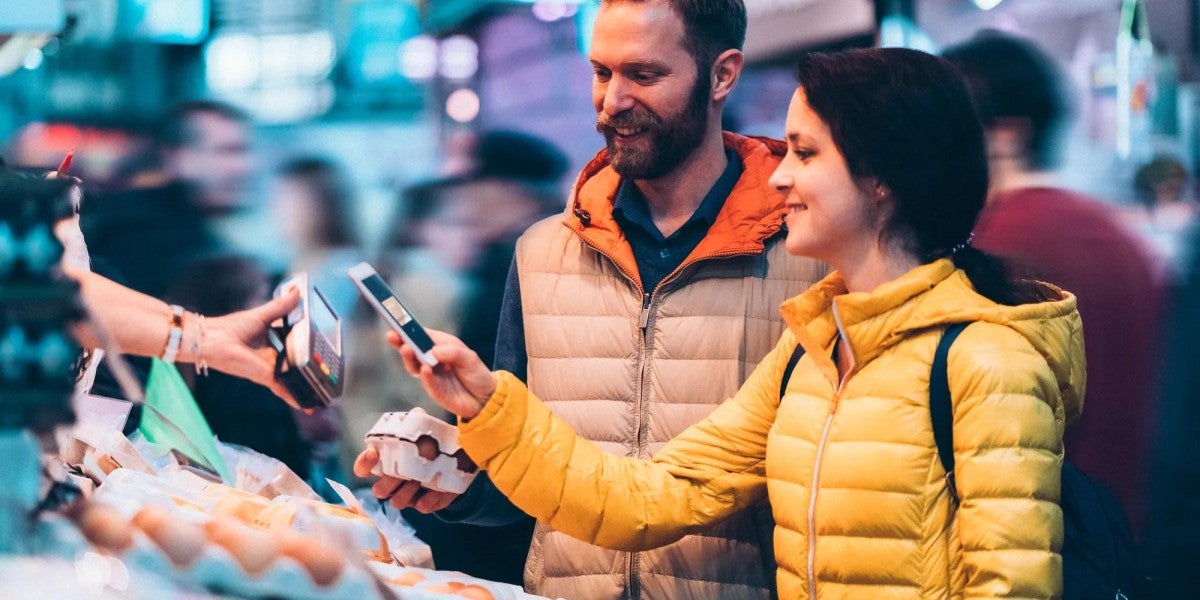 Young couple buying eggs on the street market using tap to pay.