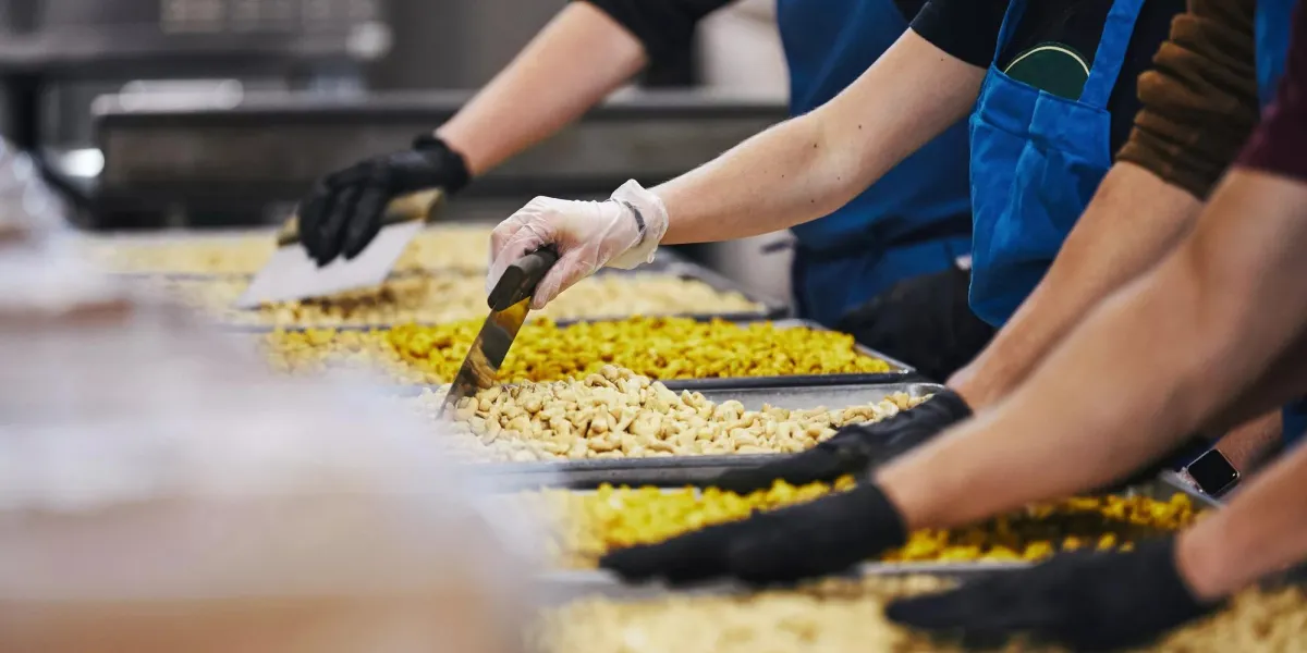Three workers in a kitchen, prepping to serve food to people in need.
