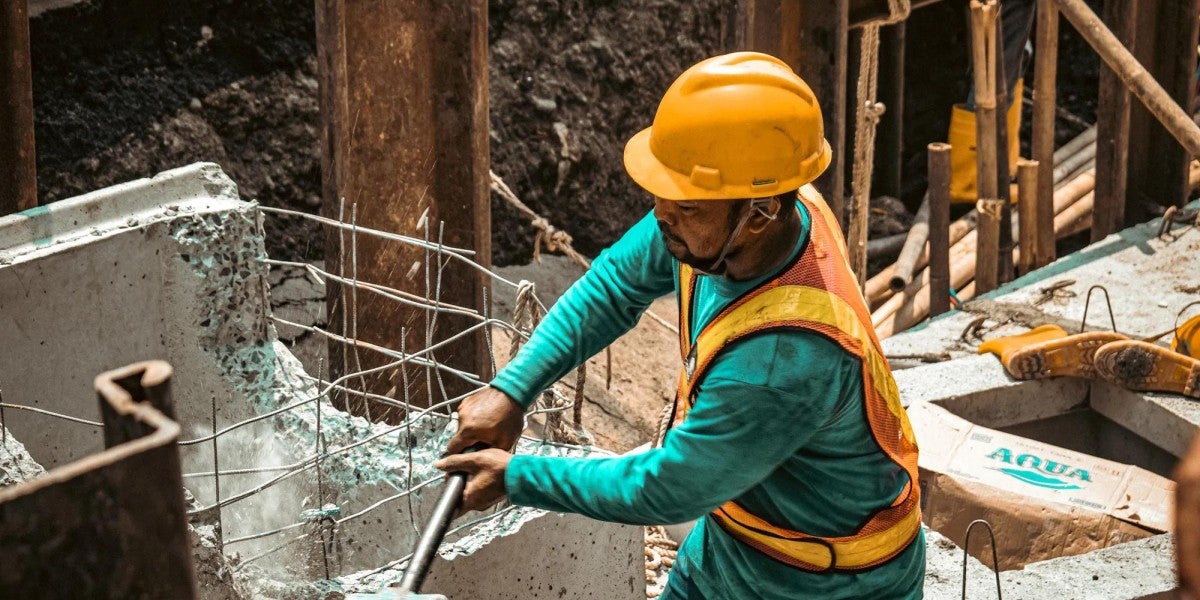 Construction worker breaking down concrete with a mallet.