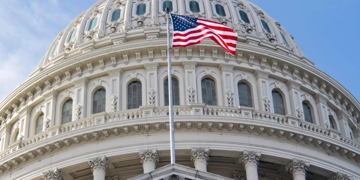 The U.S. flag flying in front of the U.S. Capitol.