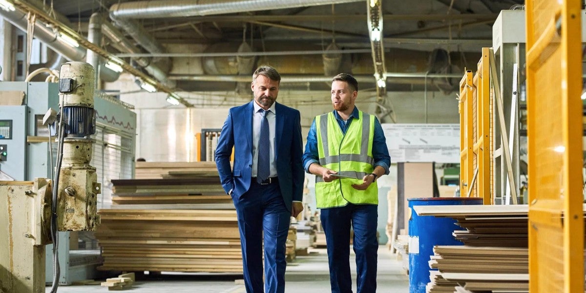 A businessmen and a construction worker walking and discussing the project they are working on.