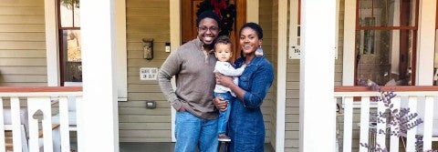 Portrait of black family and child in front of home for the holidays.