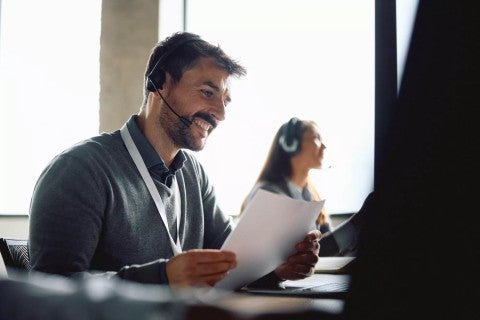 Man looking at a document with a headset on.