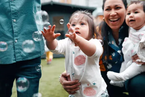 Woman with her two children, who are playing with bubbles.