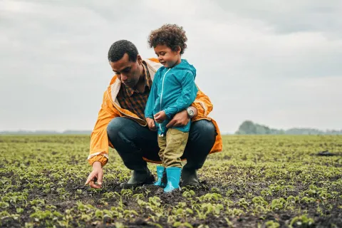 Dad and child outside exploring a field.