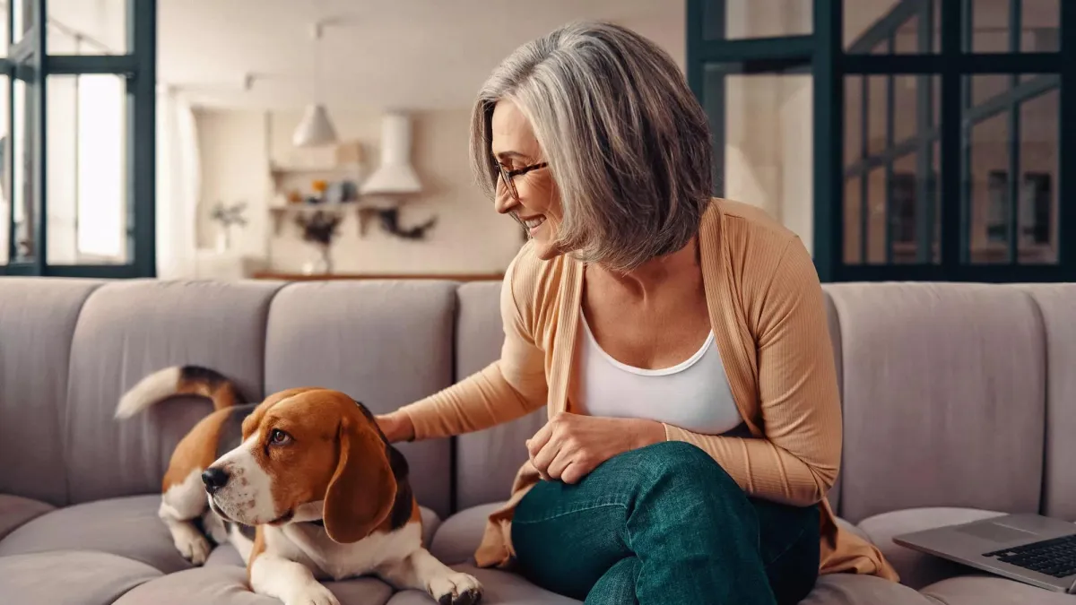 A woman sitting on a sofa with her dog.