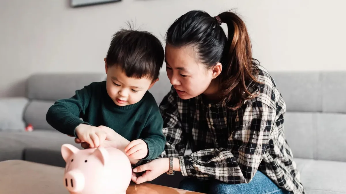 A mother and her child putting coins in a piggy bank.