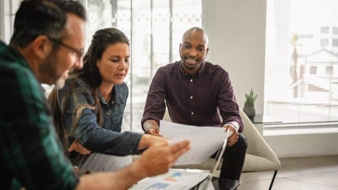 Three employees work together to review retirement solutions. Three employees work together to review retirement solutions.