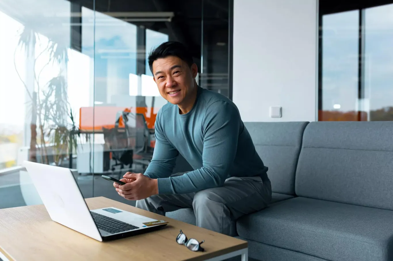 Asian male working on the couch with a laptop.
