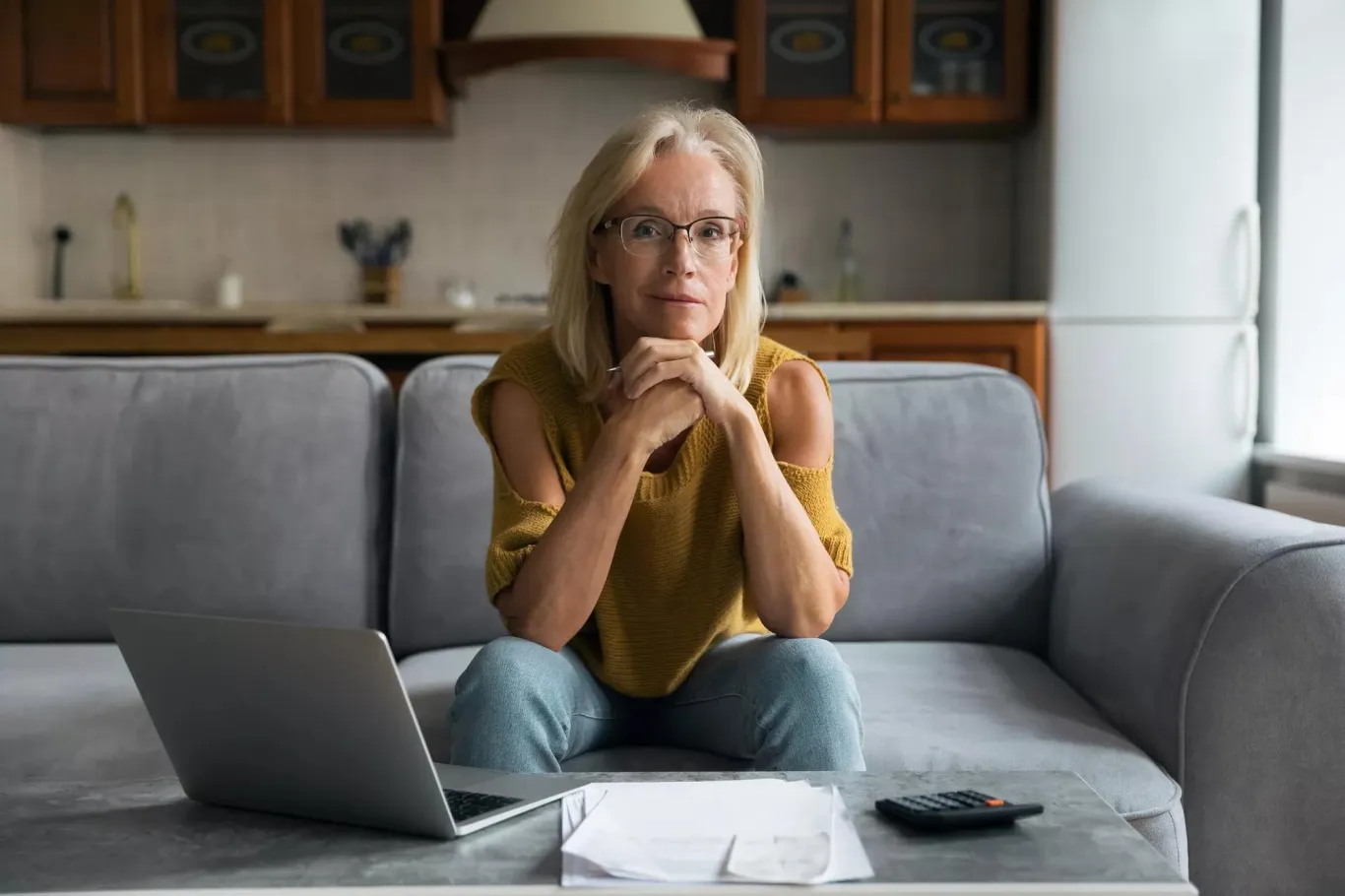 Older white woman on the couch working at her laptop.