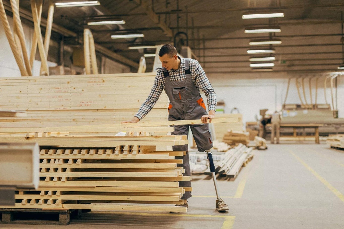 Man with prosthetic leg selecting lumber for manufacturing Man with prosthetic leg selecting lumber for manufacturing