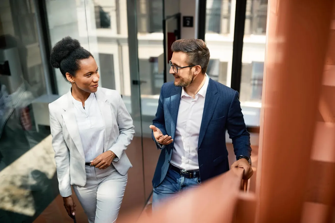 Two professionals walking through an office building during a business discussion.