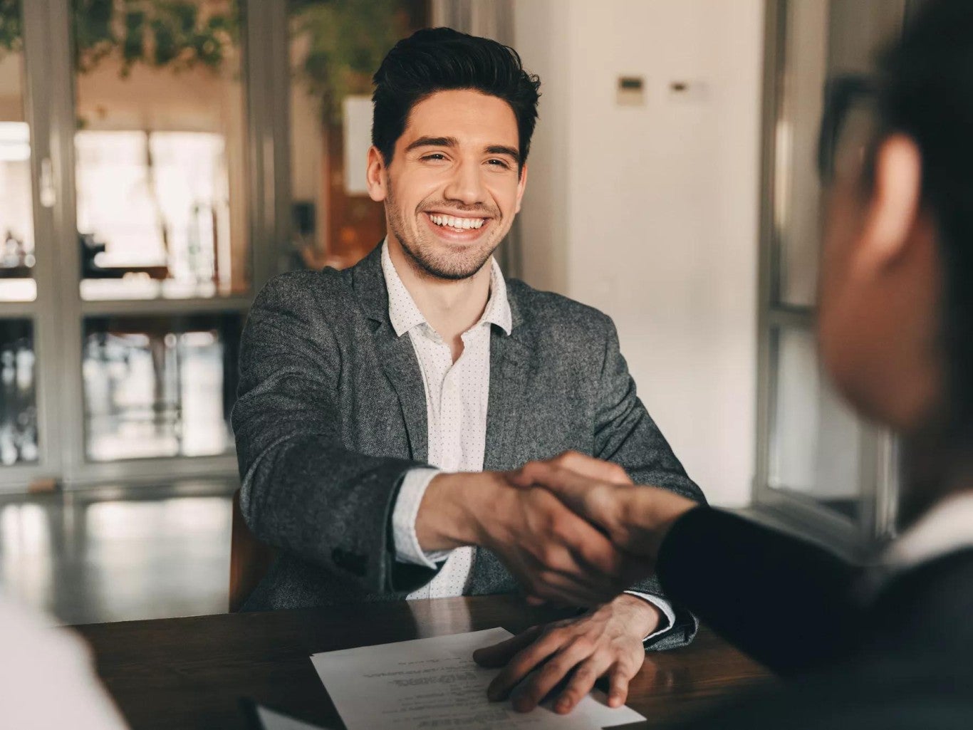 Young man shaking hands across a desk. Young man shaking hands across a desk.