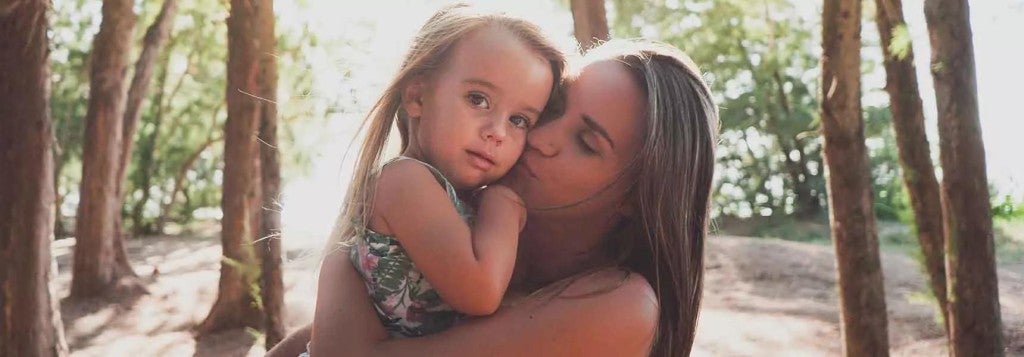 A young mother holding her preschool age daughter.