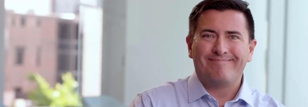 White man with brown hair smiling in an office