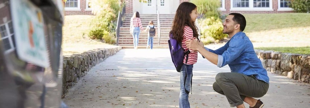 A father dropping off his daughter at school.