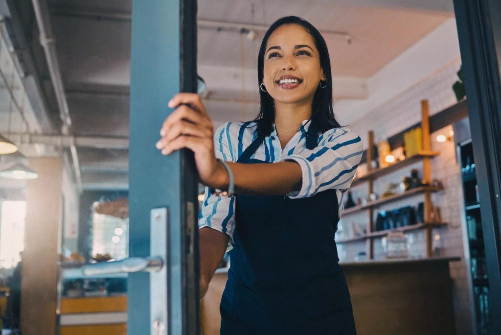 Individual disability insurance Woman holding open the front door of her business.