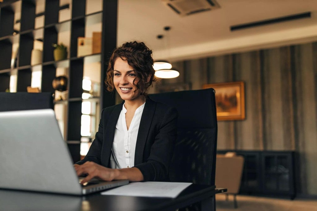 Principal Income protection Woman at desk working on a laptop.