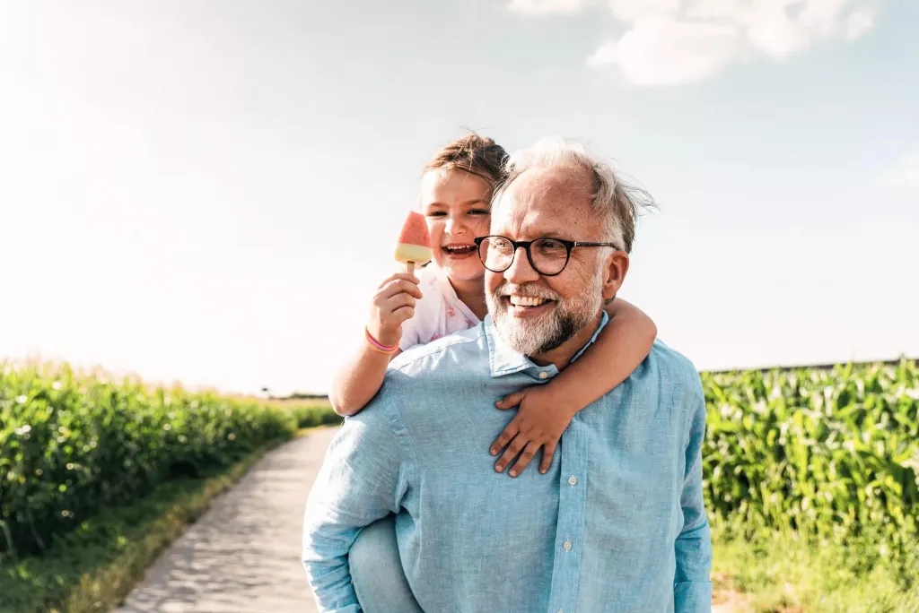 A happy man and his grandchild walking outdoors.