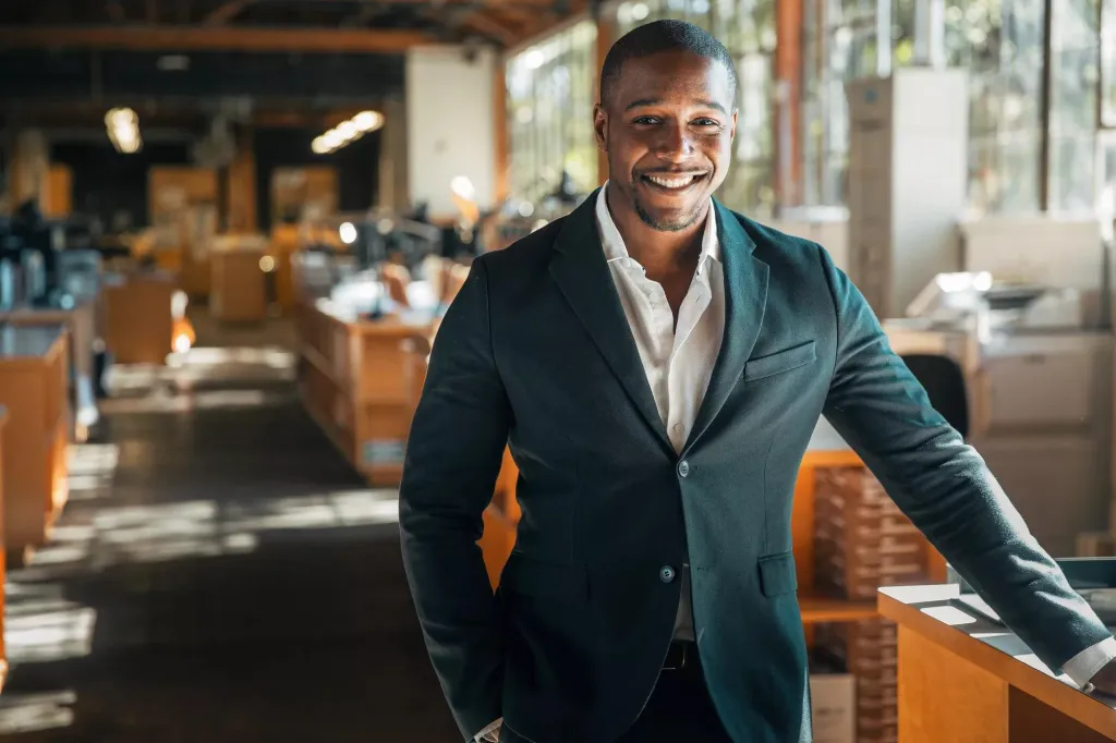 A business professional standing in a relaxed office setting.