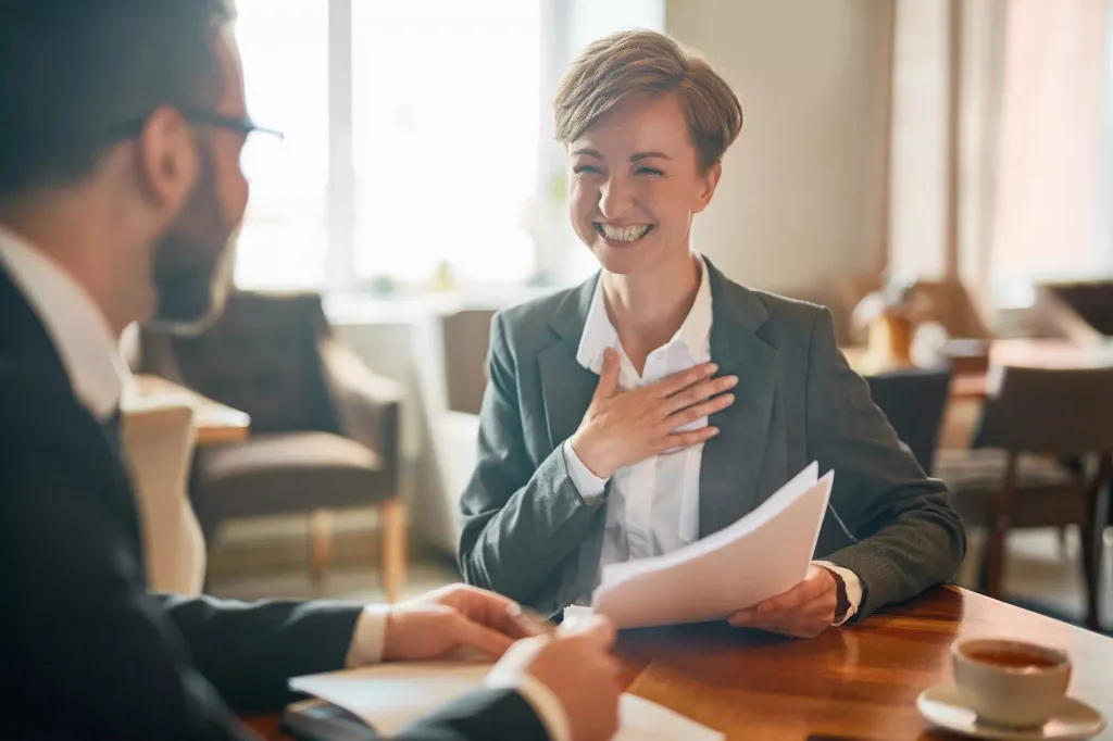Woman holding open the front door of her business.