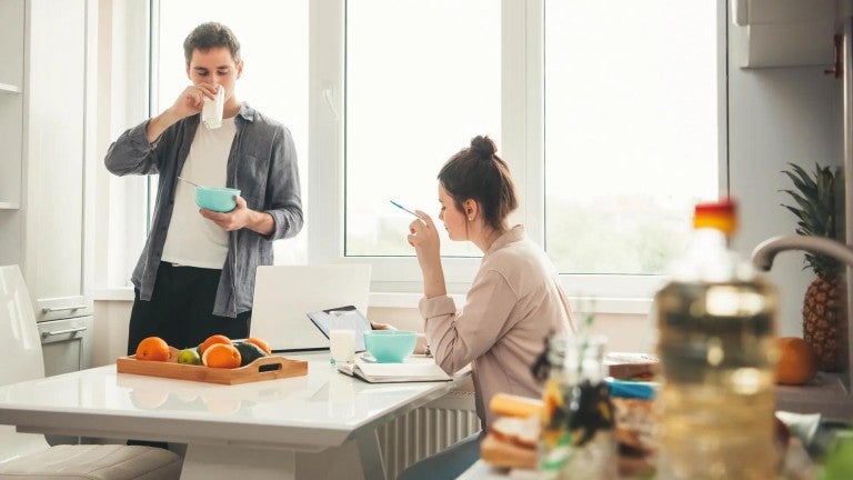 Young male and female couple eating breakfast at home while going over finances.