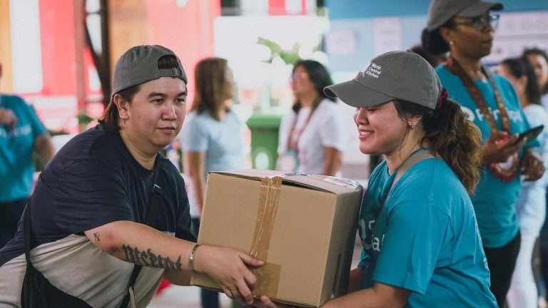 Principal employees work together to carry a box at the World Central Kitchen volunteer event.