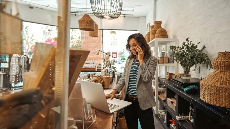 Woman talking on the phone while working on her laptop.