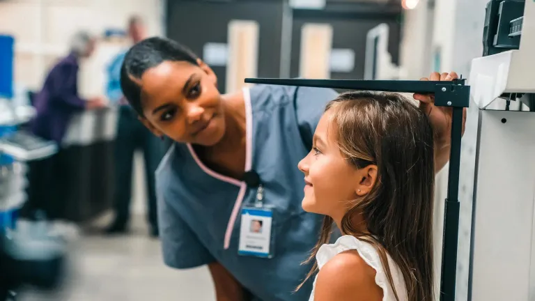 Nurse measuring height of girl