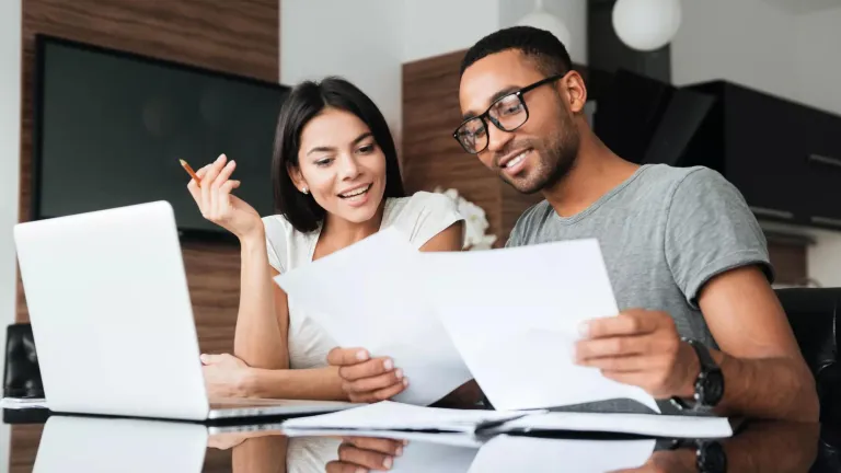 Young man and woman working together at a table to create a retirement plan.