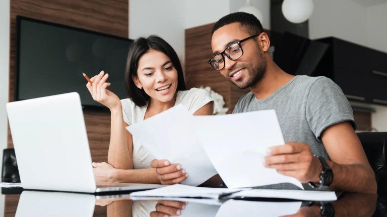 Young man and woman working together at a table to create a retirement plan.
