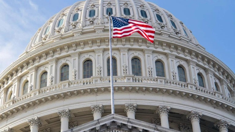 The U.S. flag flying in front of the U.S. Capitol.