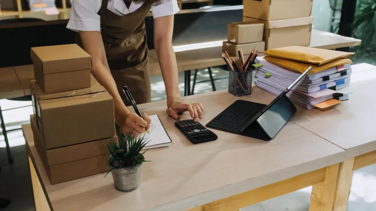 A person writing on a notepad in a retail setting.