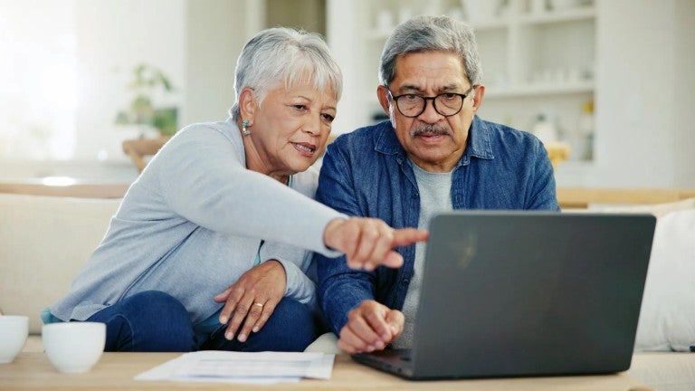 A man and woman looking at a laptop in their home.