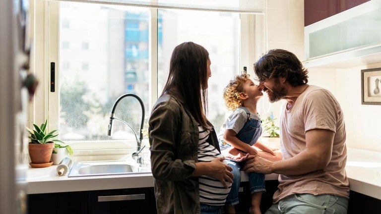 A young family sharing a tender moment in their kitchen.
