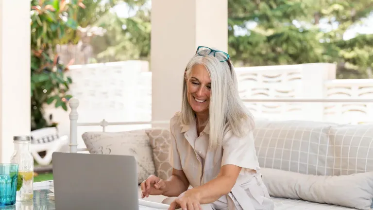 Middle-age woman sitting on couch looking at her computer