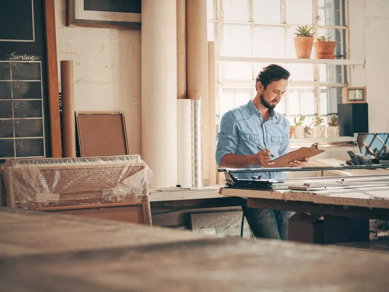 A person working at a wooden desk in a casual office or home workspace environment.