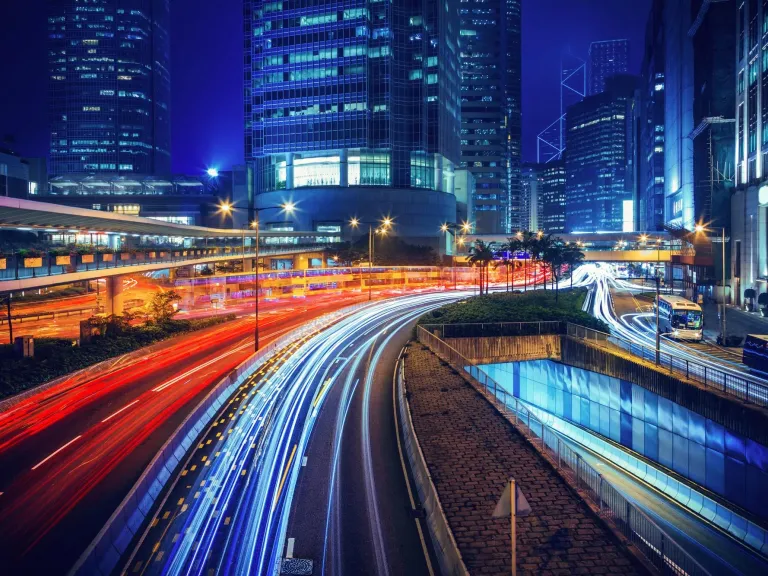 Long exposure nighttime photograph of a curved highway in a modern city.