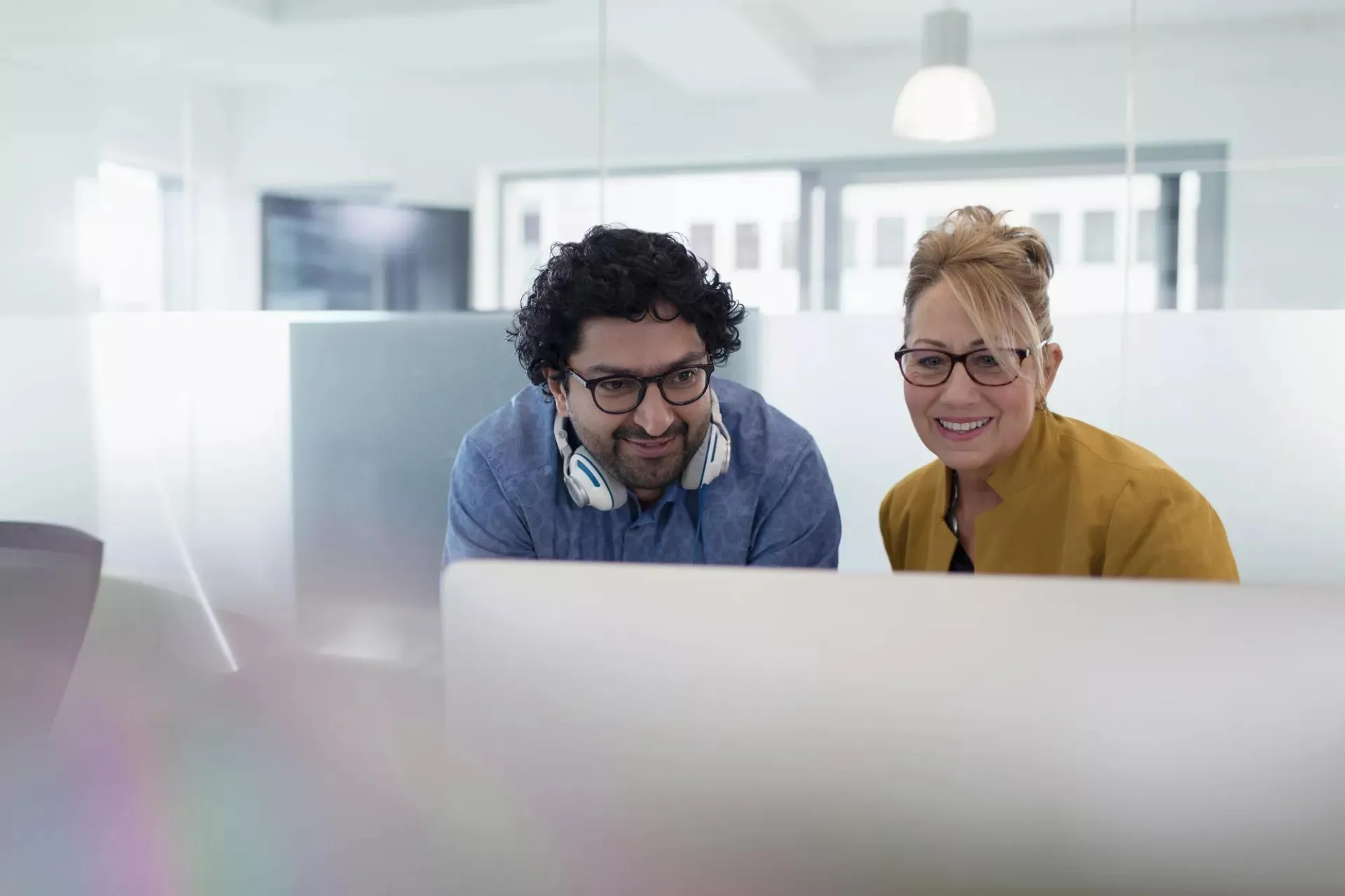 Two smiling coworkers looking at the same screen.