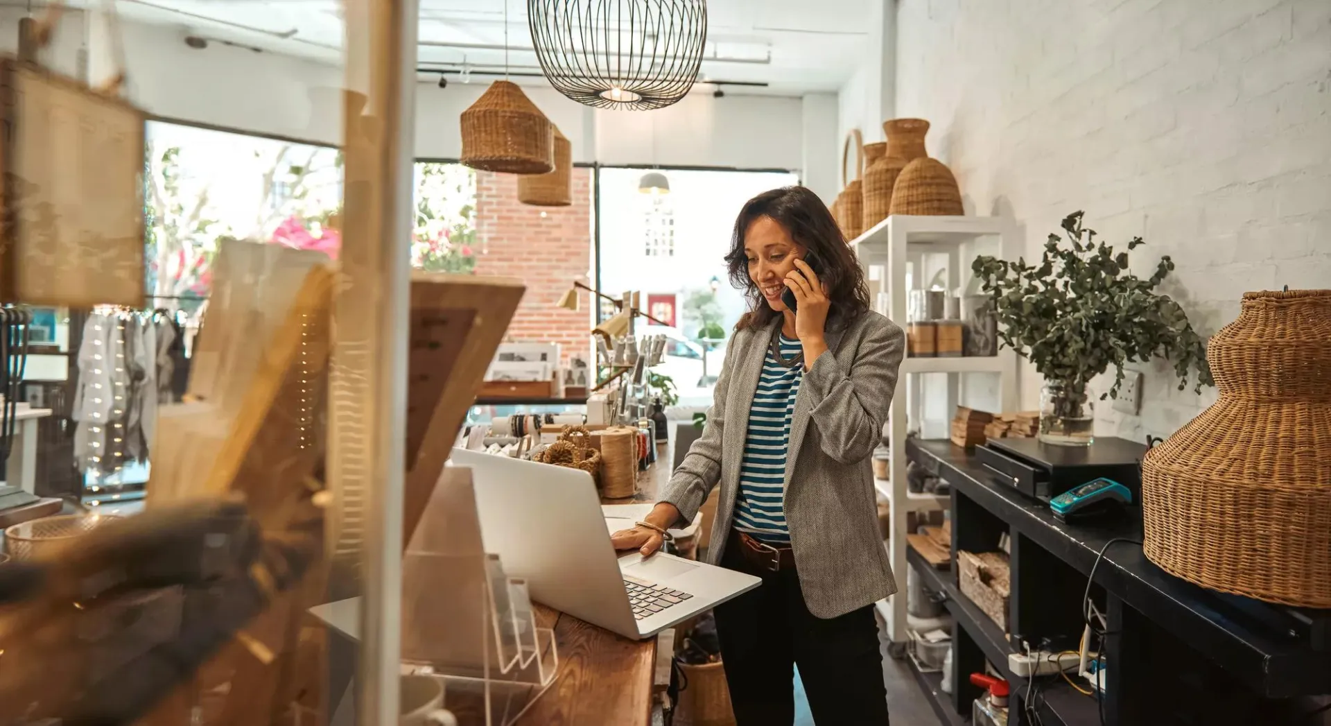 Woman talking on her phone while working on her laptop.