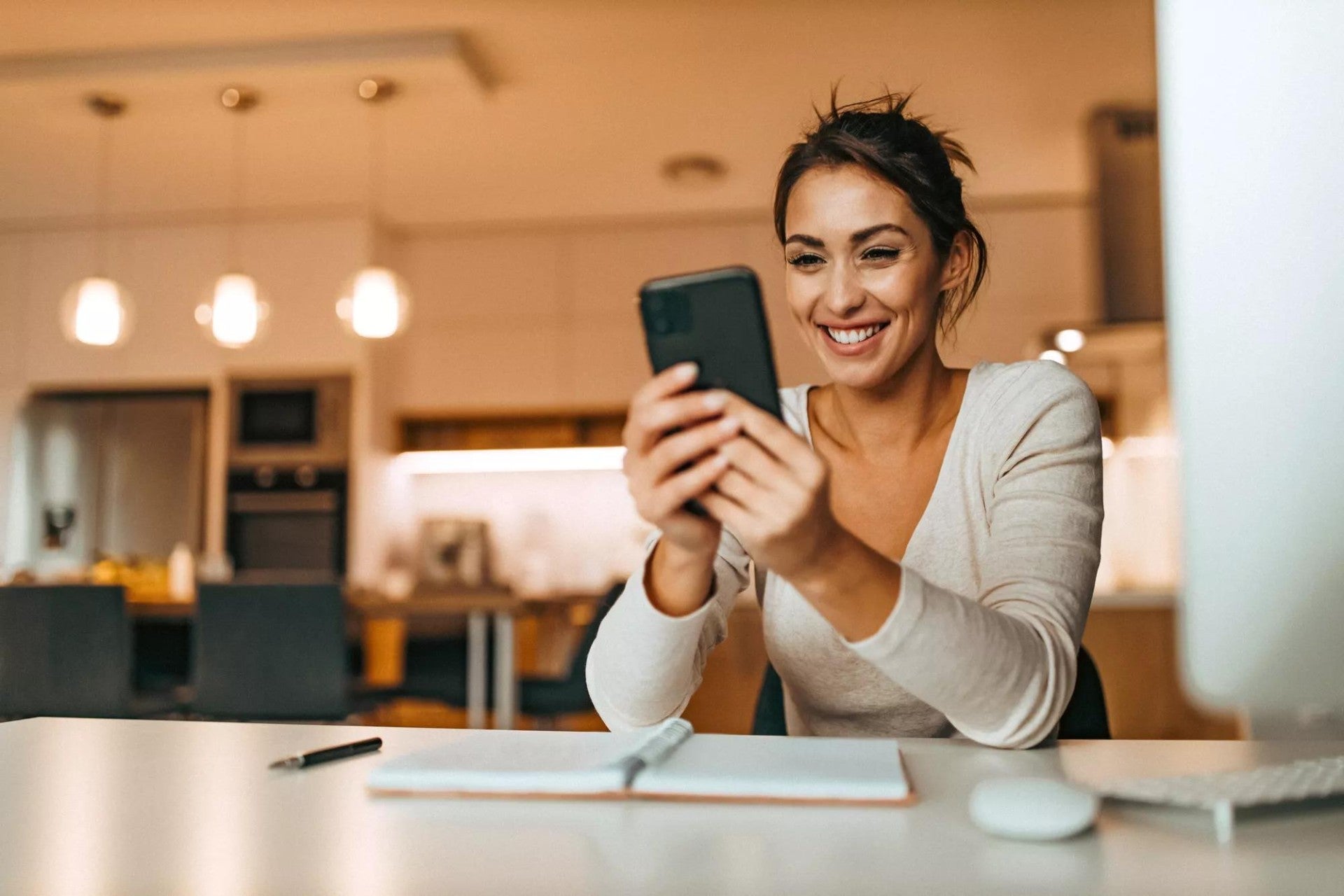 Women sitting at her desk checking her phone.